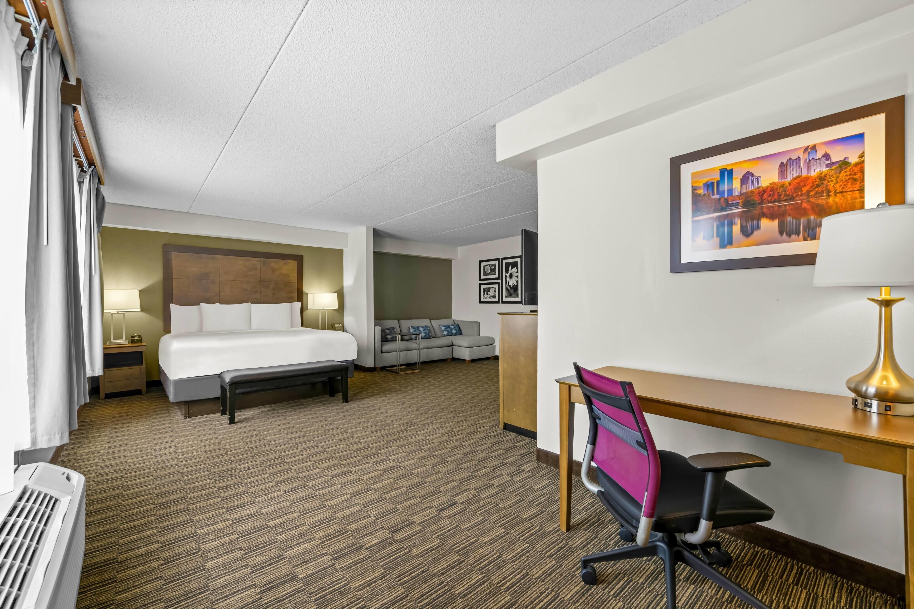 Une chambre d’hôtel avec un lit, un bureau, une chaise et un canapé.