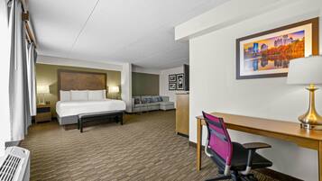 Une chambre d’hôtel avec un lit, un bureau, une chaise et un canapé.