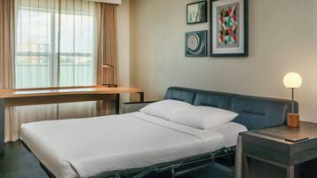 Una habitación de hotel moderna con una cama, una mesita de noche, una lámpara y obras de arte en la pared.