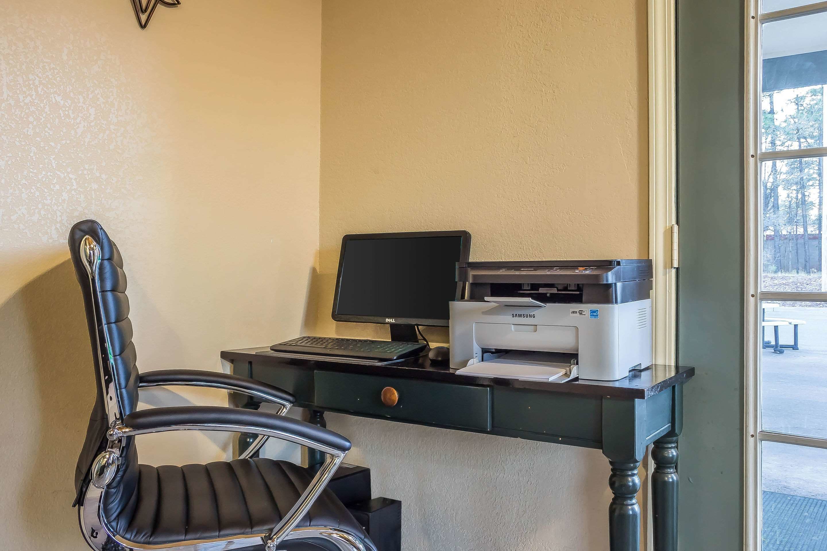 Un bureau avec un ordinateur, une imprimante et une chaise.