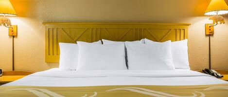 A neatly made bed with white linens and a yellow headboard, flanked by two bedside lamps with elephant-shaped shades.
