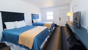 A hotel room with two beds, a desk, a television, and a window. - The Brooke Hotel (Brookshire)