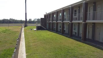 A multi-story motel with individual rooms, a small outdoor area, and a parking lot.