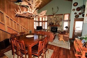 Un interior de madera con una mesa de comedor, sillas, chimenea y pared de piedra.