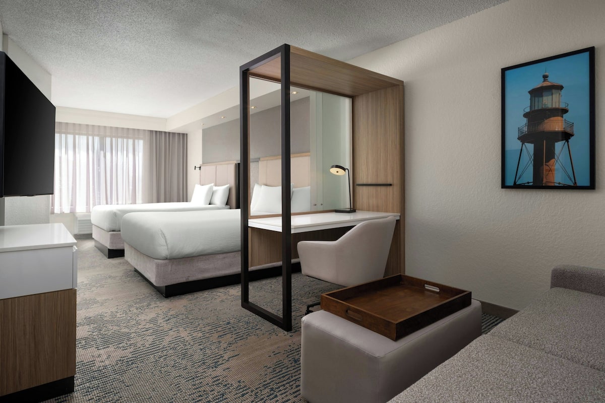 Une chambre d’hôtel avec un lit, un bureau, une chaise et une petite table.