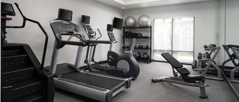 A modern gym with treadmills, elliptical machines, and free weights.