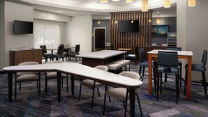 A modern hotel lobby with a long reception desk, seating area, and a television mounted on the wall. - SpringHill Suites by Marriott Fort Myers Airport (Fort Myers)