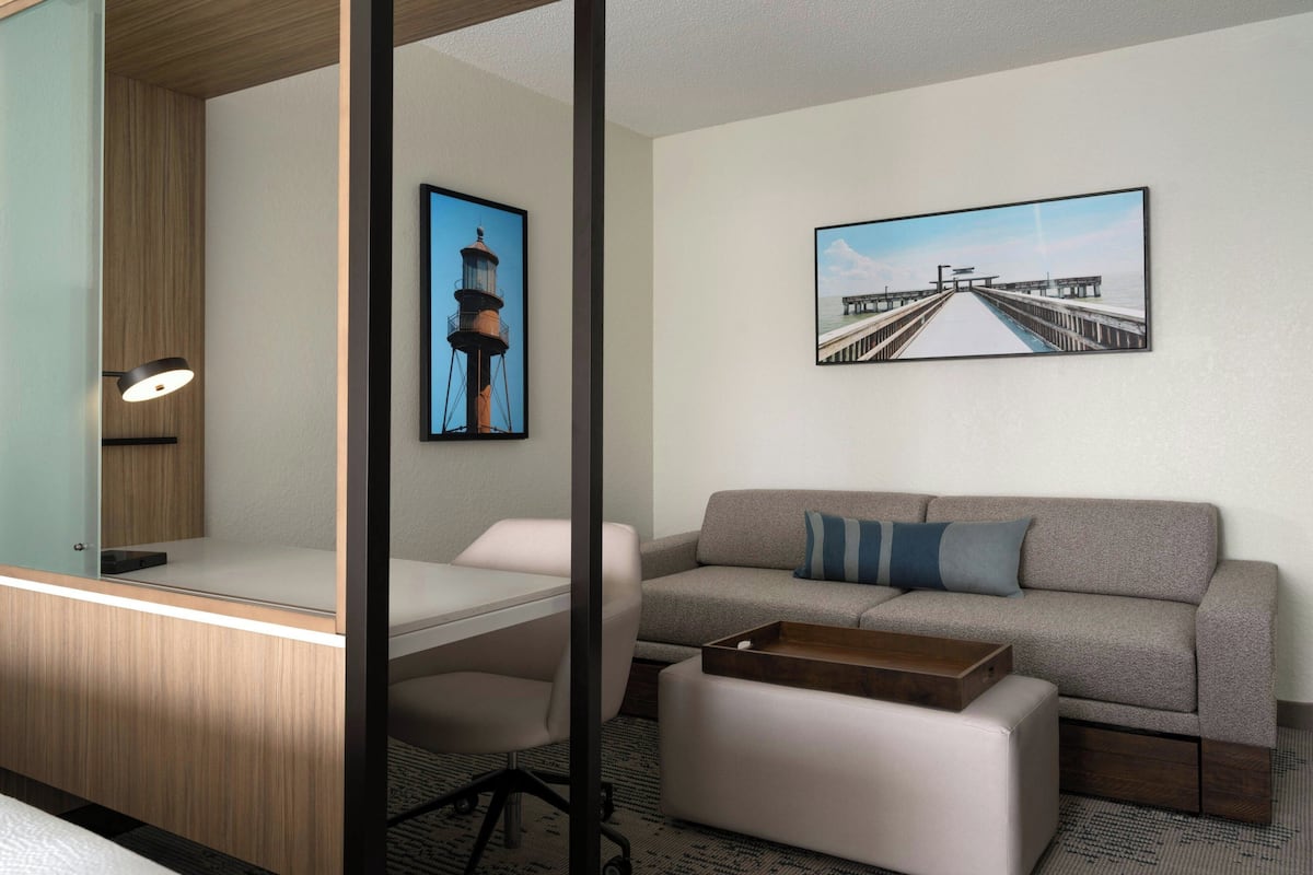 Une chambre moderne équipée d’un bureau, d’un canapé et de deux tableaux encadrés accrochés au mur.