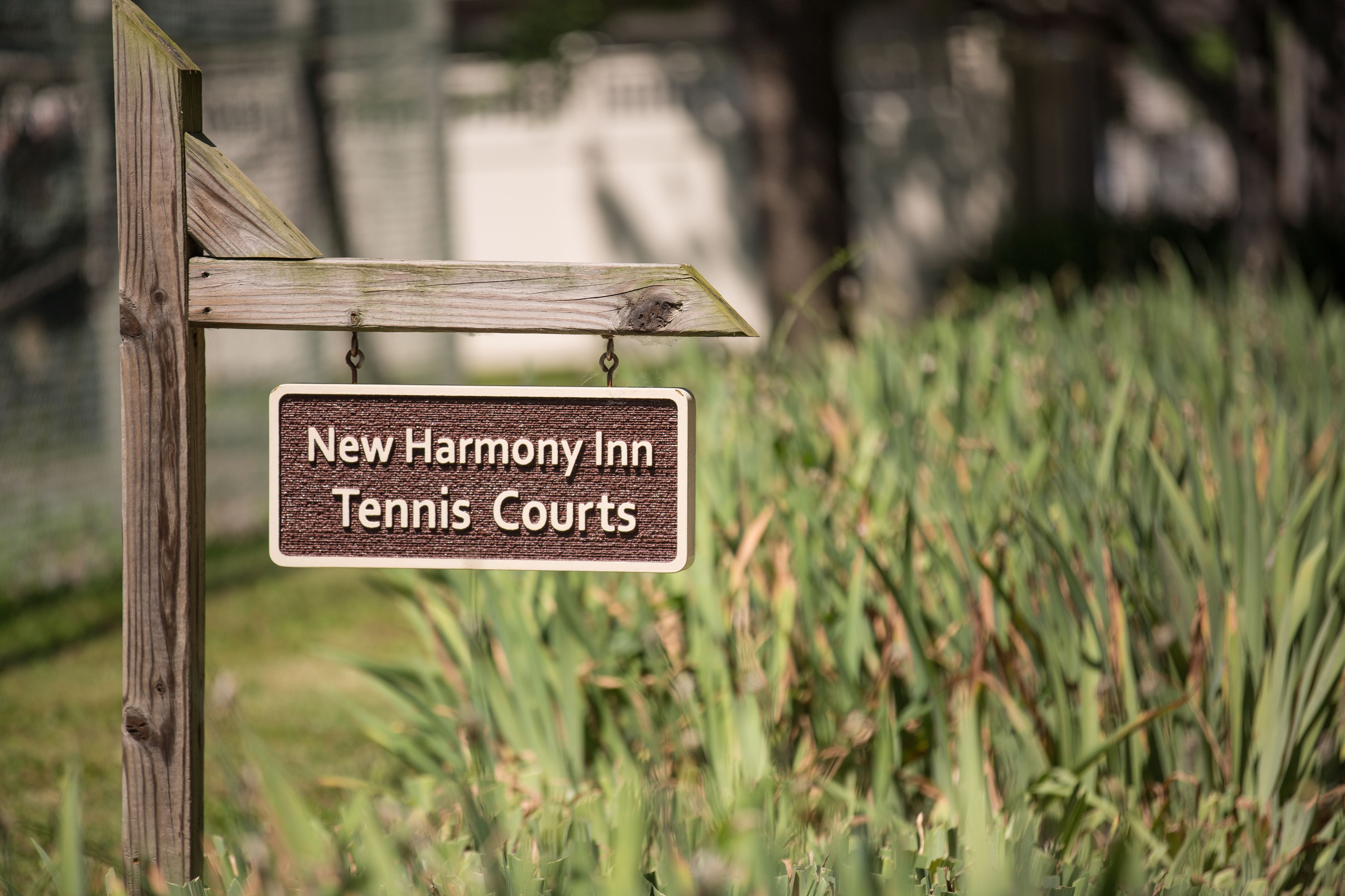 A wooden signpost with a sign that reads "New Harmony Inn Tennis Courts."