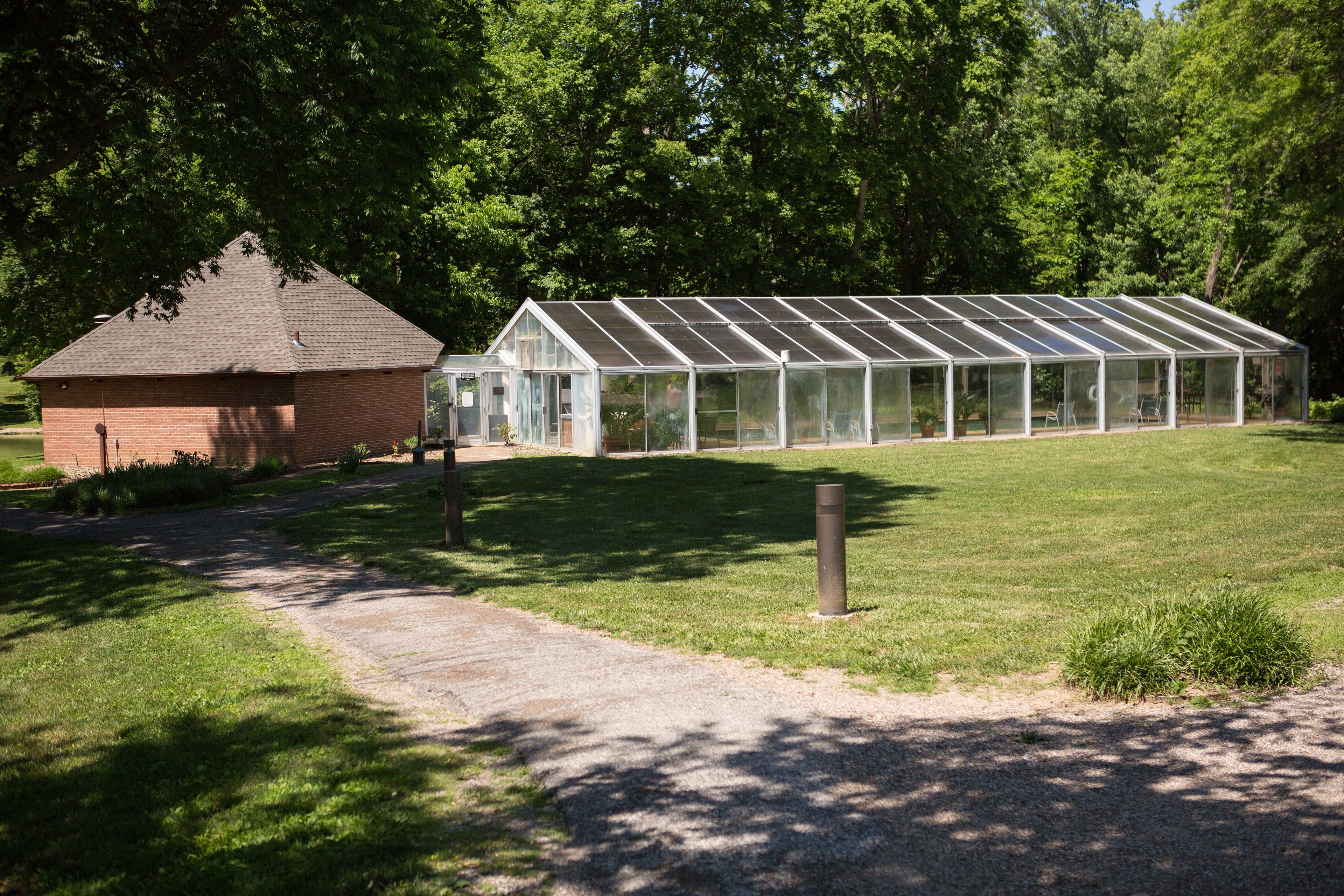 A greenhouse structure with a glass roof and a brick building adjacent to it.