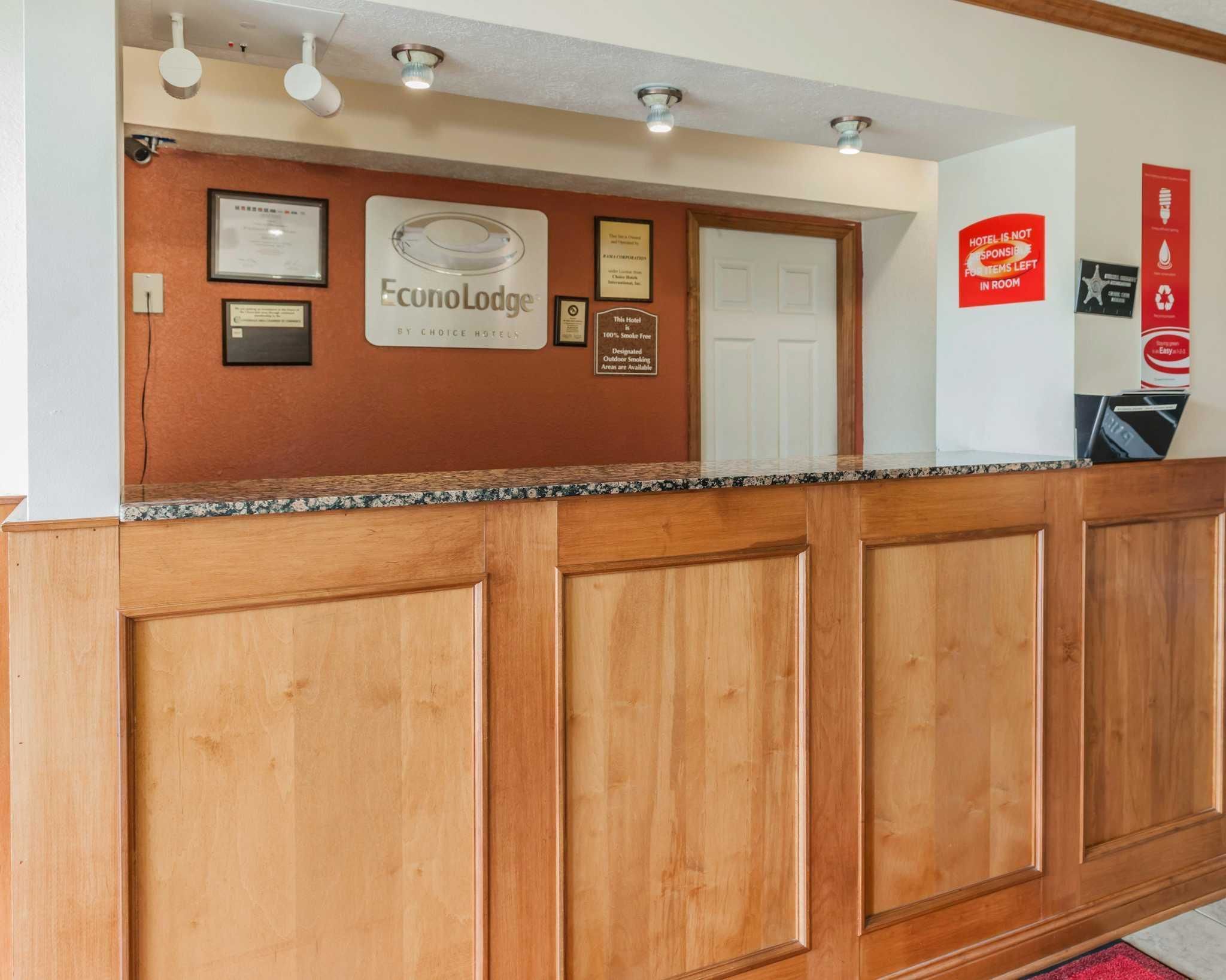 A reception desk with a wooden panel design, framed certificates, and a sign for EconoLodge by Choice Hotels.