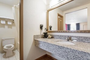 A bathroom with a granite countertop sink, a large mirror, and a toilet. - Econo Lodge Cloverdale (Cloverdale)