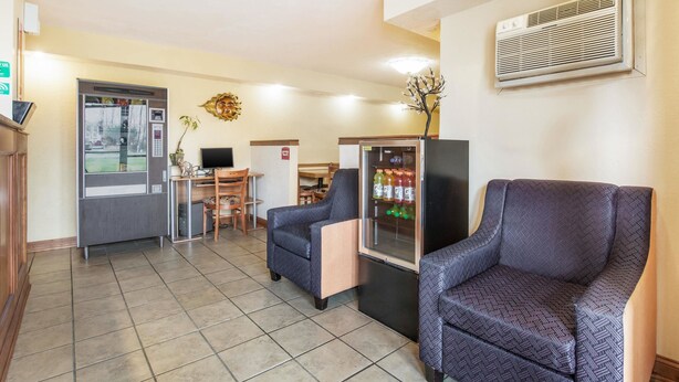 Un vestíbulo de hotel con mostrador de recepción, zona de estar, máquina expendedora y unidad de aire acondicionado.