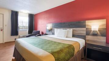 Una camera d'albergo con un letto, una scrivania, una sedia e una finestra con tende.