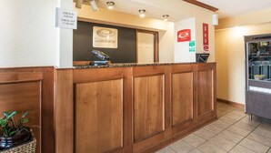 Una mesa de recepción con un letrero que indica los horarios de registro de entrada y salida, el logotipo de Econolodge y una máquina expendedora de aperitivos.