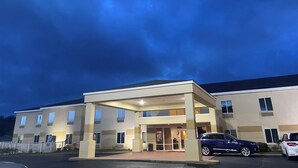 Ein mehrstöckiges Hotel mit überdachter Eingangsparte und Parkplatz.