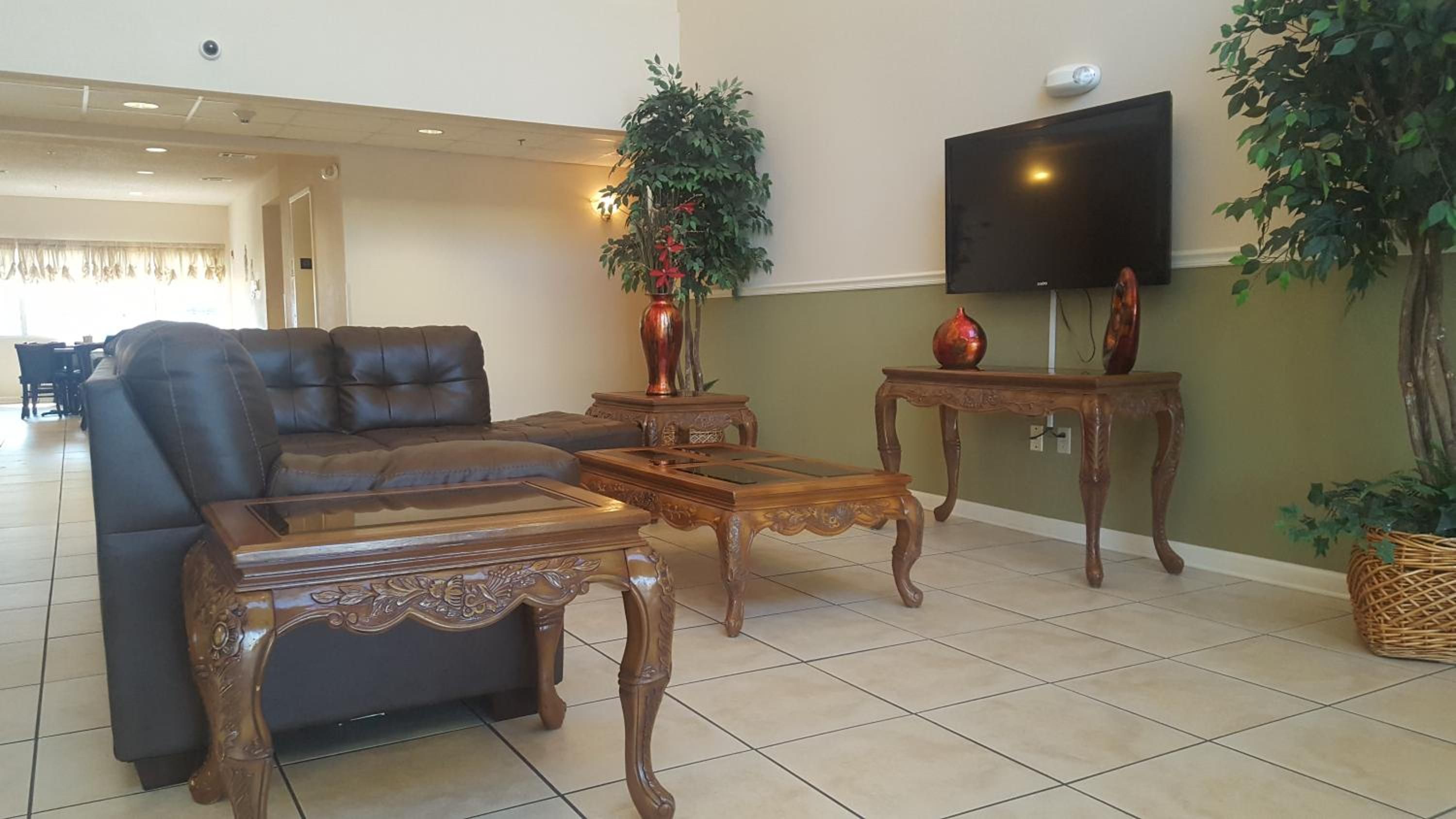 A living room with a leather sofa, wooden coffee table, and a flat-screen TV mounted on the wall.