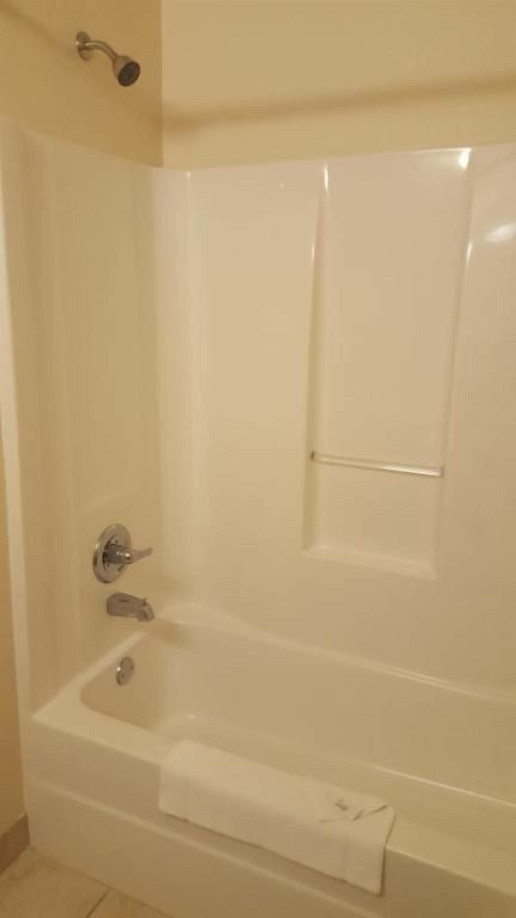 A bathroom with a bathtub, a shower, and a towel rack.