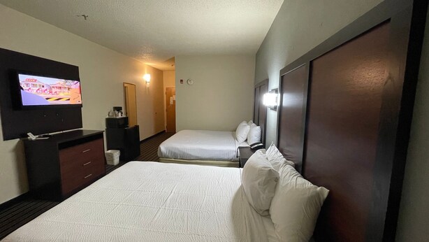 Ein Hotelzimmer mit zwei Betten, einem Fernseher an der Wand, einem Schreibtisch und einem Spiegel.