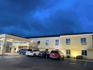 A parking lot with several cars parked in front of a building with multiple windows and a flat roof.