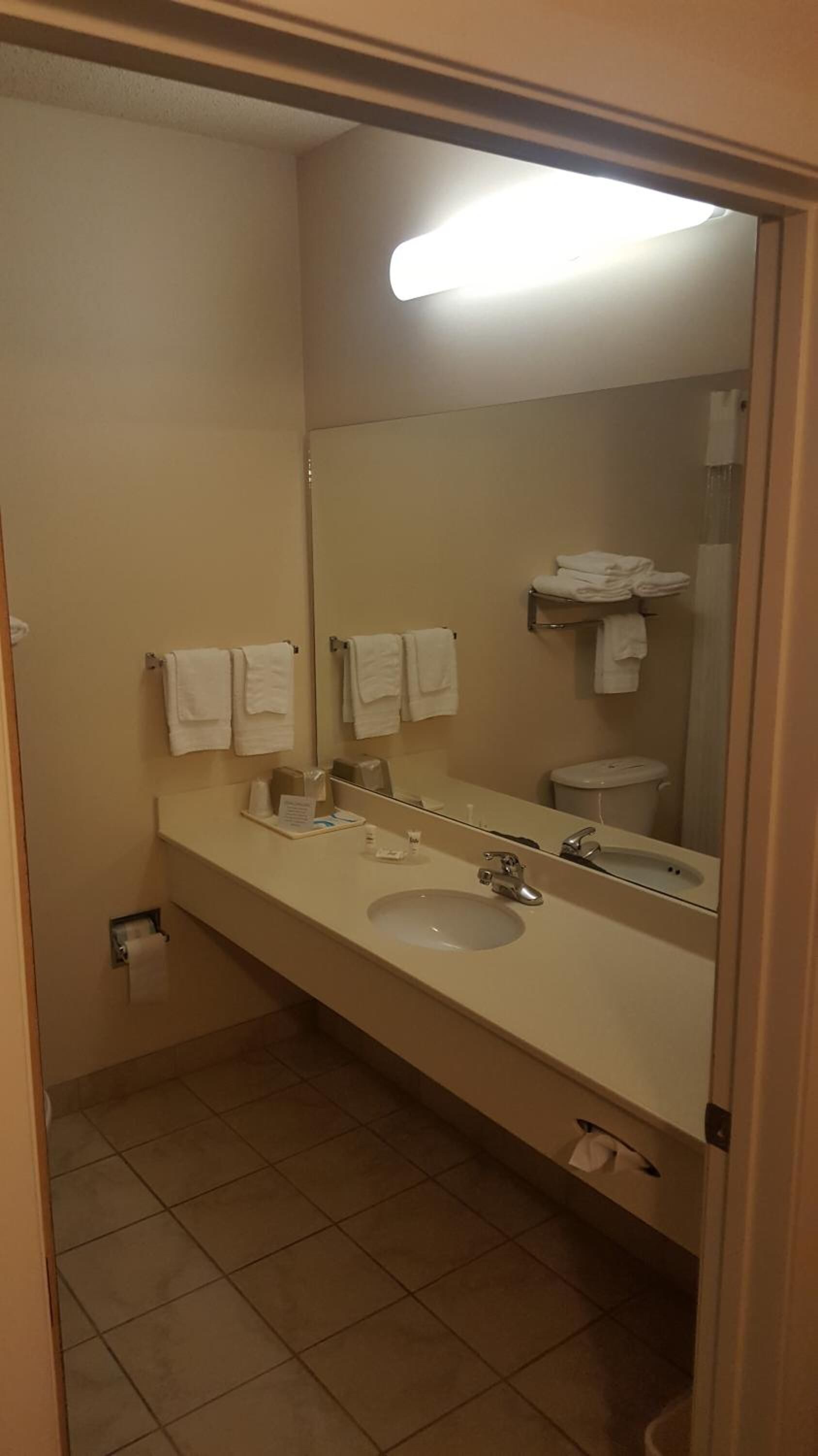 A bathroom with a sink, mirror, and two towels hanging on the wall.