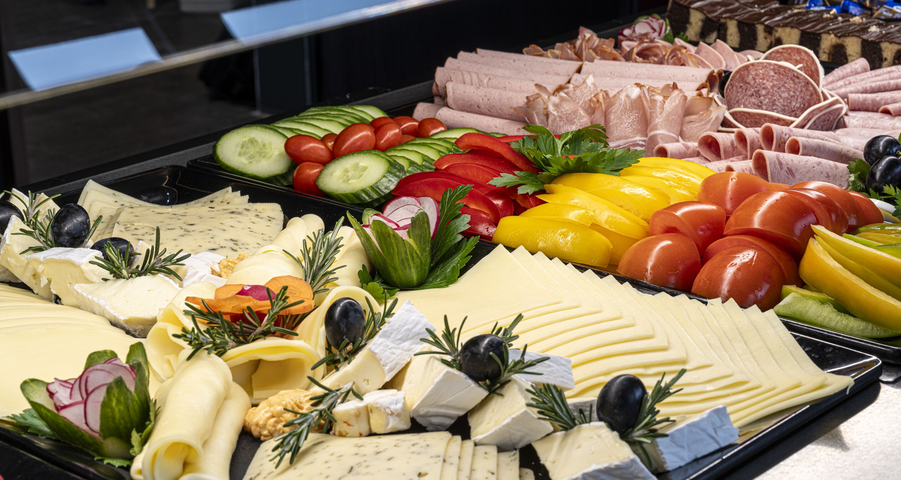 A variety of cheeses, cured meats, and fresh vegetables on a tray.