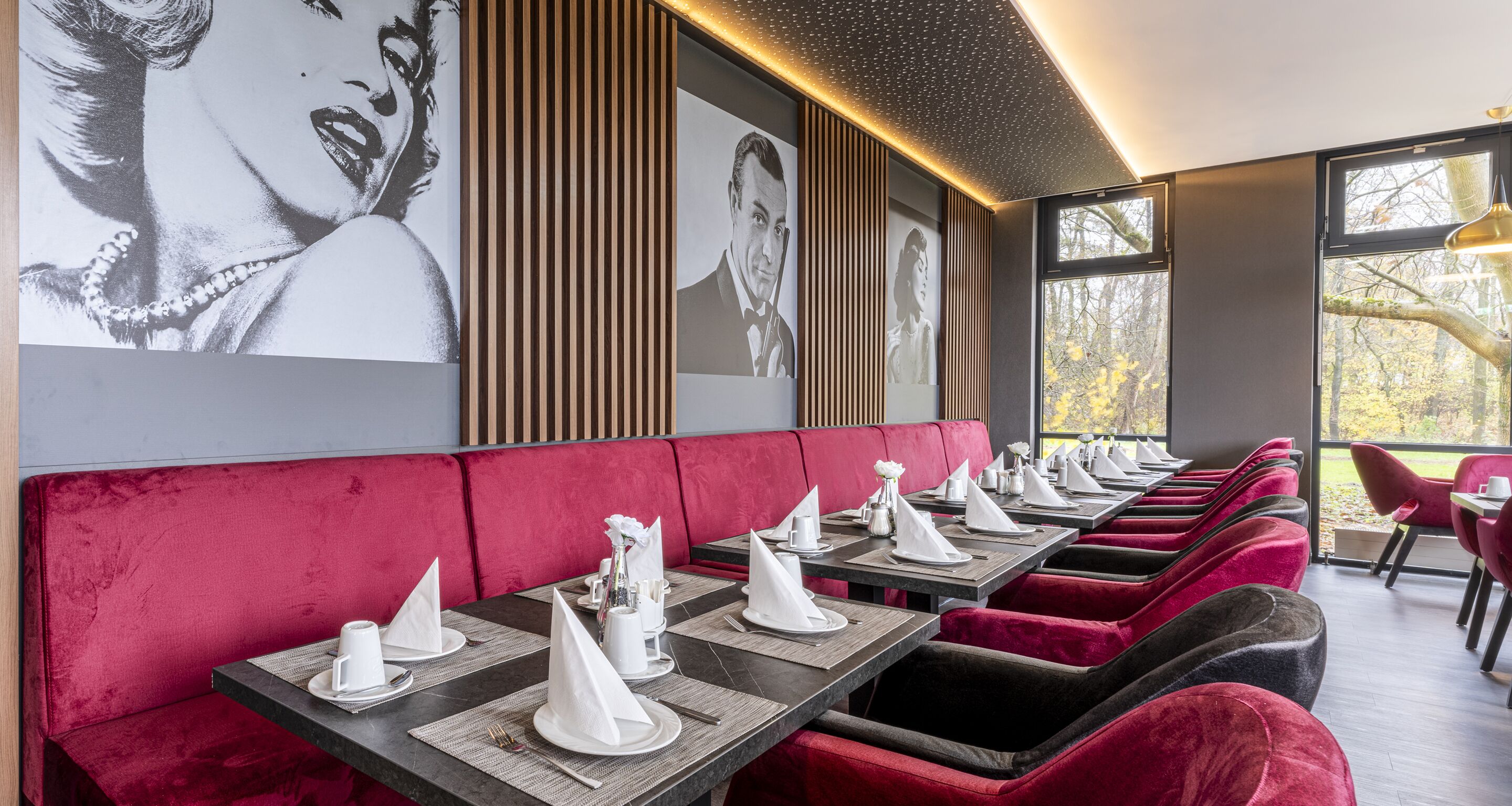 A restaurant with red velvet booths, black tables, and white napkins.