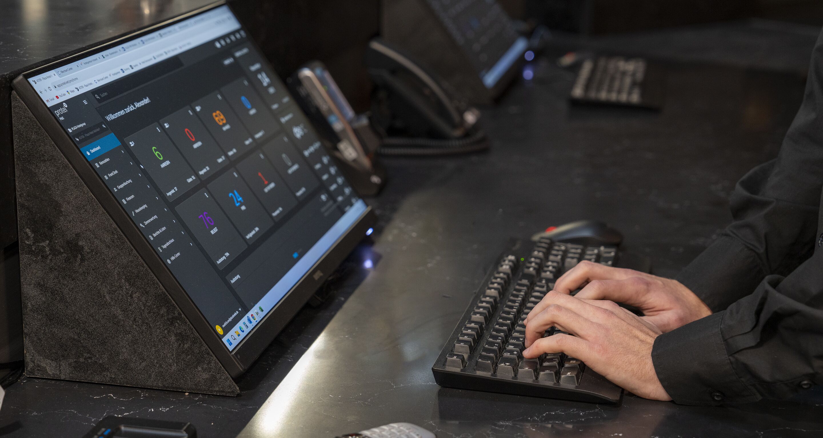 A person using a laptop and a mechanical keyboard on a desk.
