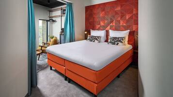 Una habitación de hotel moderna con una cama grande, un cabecero rojo estampado y vistas al exterior.