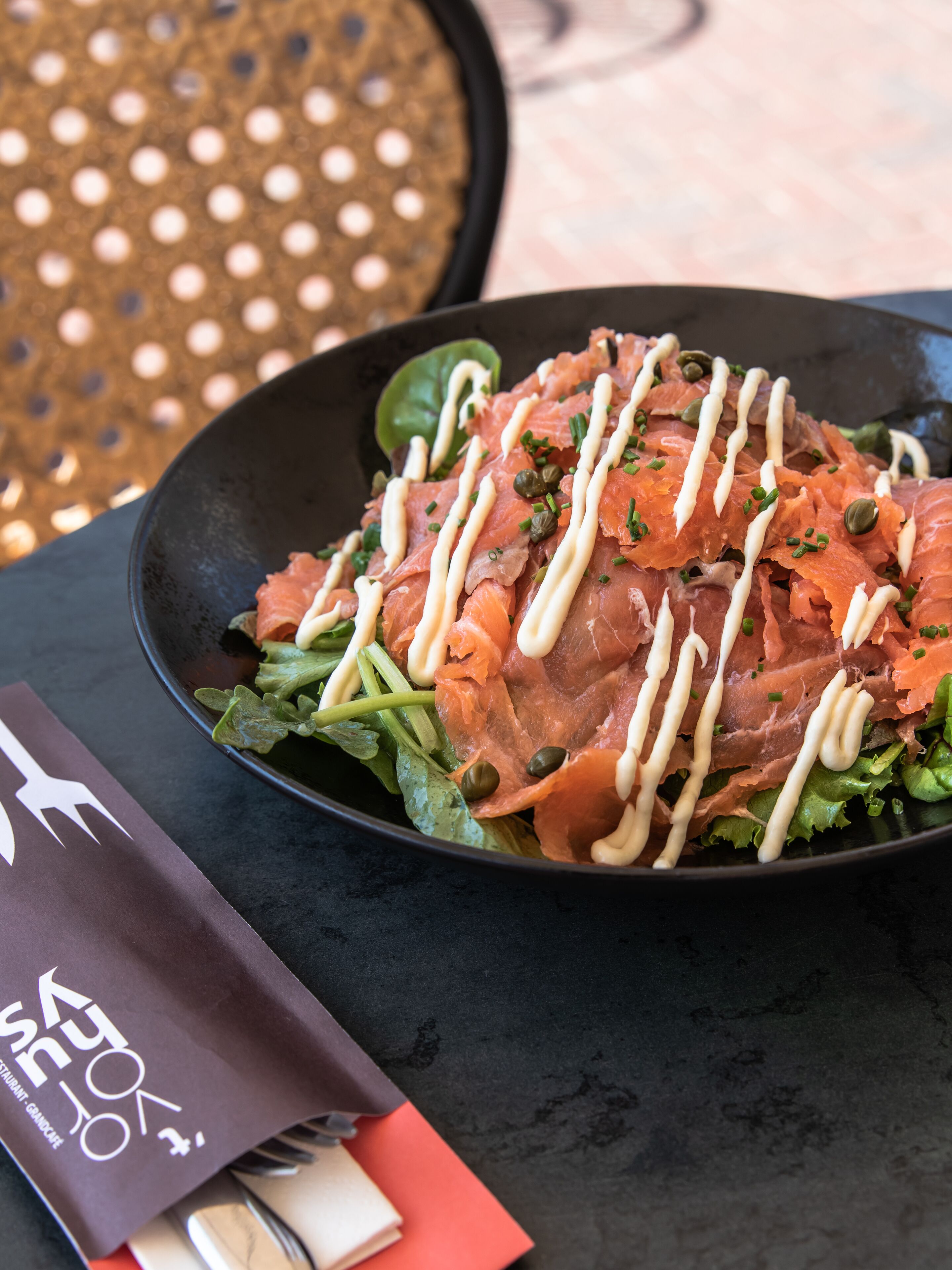 A plate of food with salmon and greens, a napkin, and a menu.