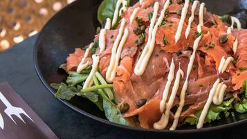 A plate of food with salmon and greens, a napkin, and a menu.