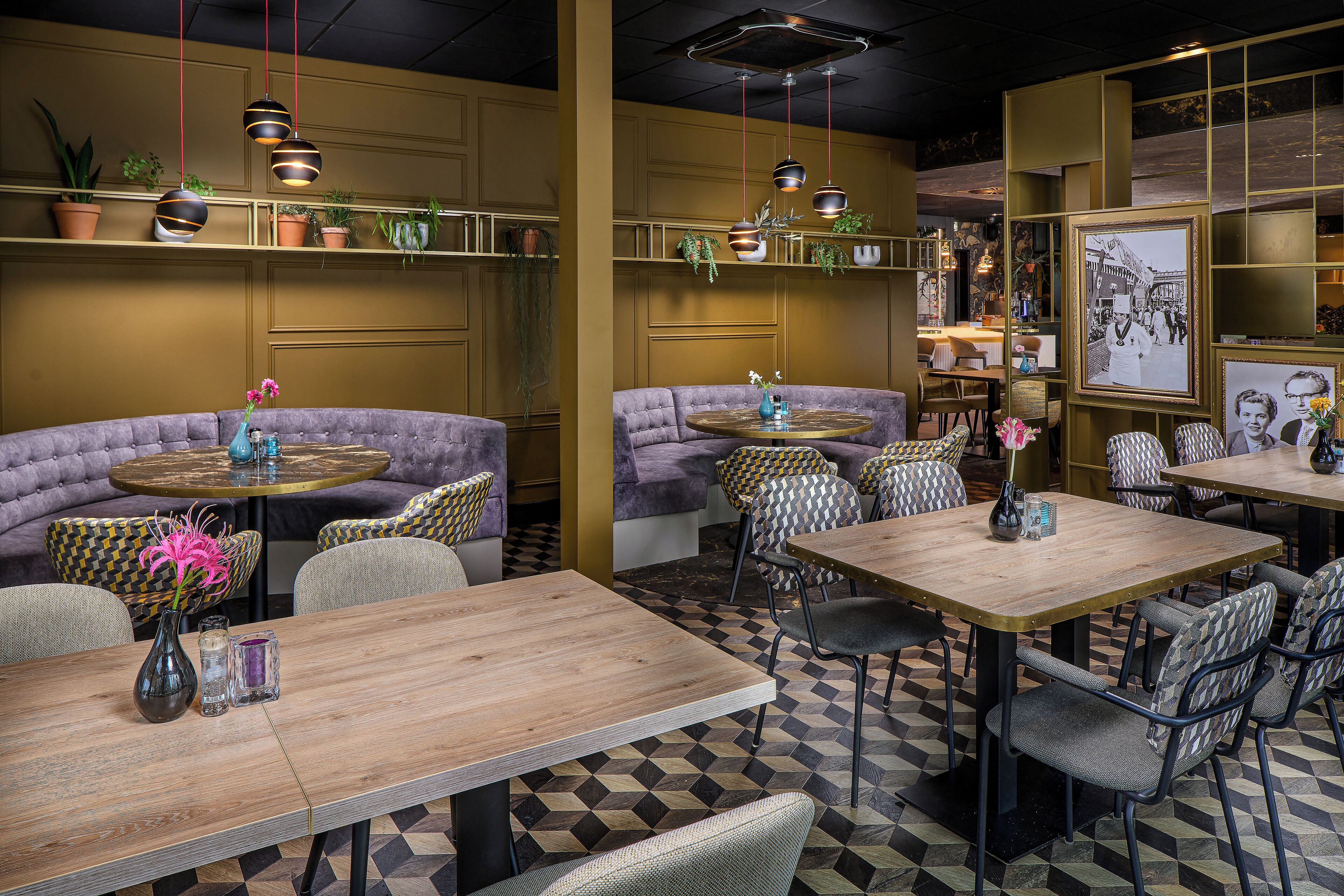 A restaurant interior with booths, tables, and hanging plants.