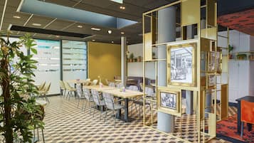 A modern conference room with a geometric patterned floor, a central table with chairs, and a decorative bookshelf with framed pictures.
