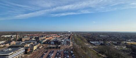 A large parking lot with multiple rows of parked cars, surrounded by buildings and a clear sky.