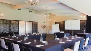 A conference room with a long table, chairs, a projector screen, and a whiteboard.