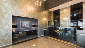 A modern lobby with a marble wall, a black reception desk, a chandelier, and a framed picture on the wall. - Croydon Lodge Hotel (Croydon)