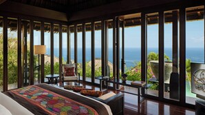 A bedroom with a large bed, a view of the ocean, and a balcony with seating. - Bvlgari Resort Bali (Pecatu)