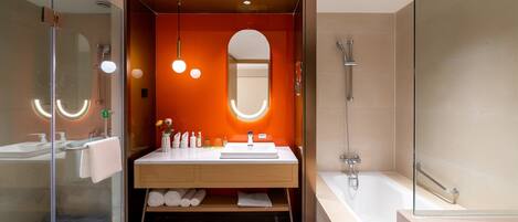 A modern bathroom with a glass shower enclosure, a white sink with a mirror, and a bathtub.