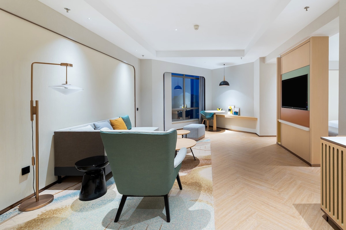 Ett modernt hotellrum med en soffa, fåtölj, soffbord och en TV.