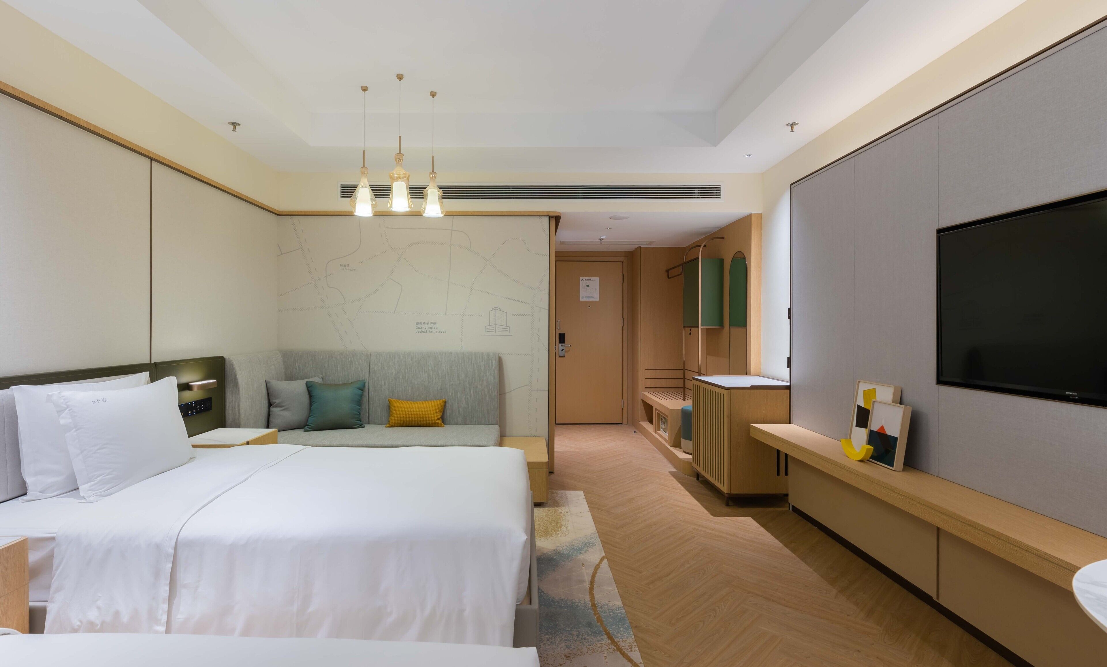 Quarto de hotel com uma cama grande, uma escrivaninha, uma televisão e um mapa na parede.