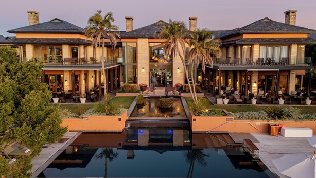A luxurious hotel with a central courtyard, outdoor seating areas, and a swimming pool.