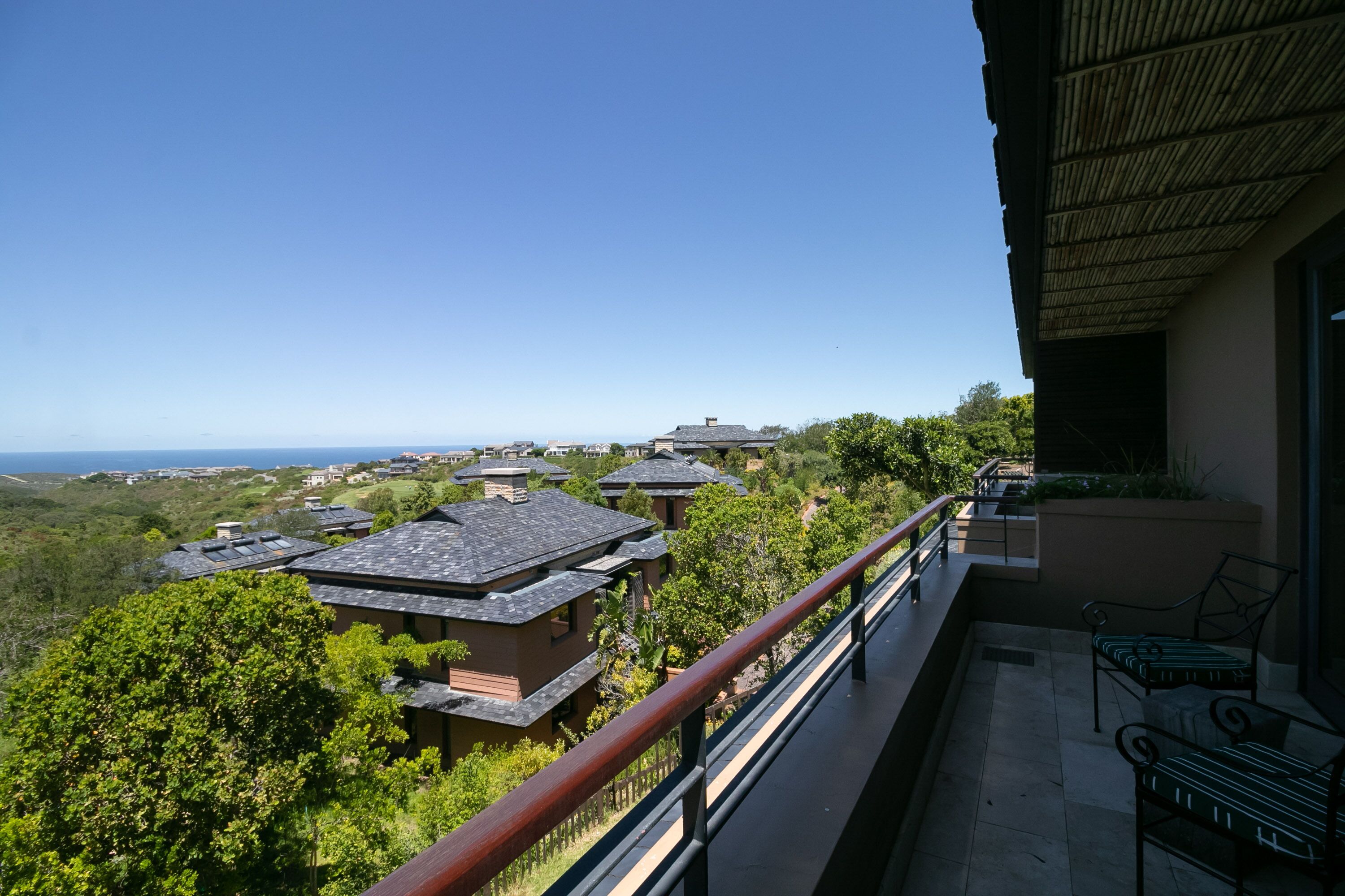 A balcony with a view of a residential area and the sea.