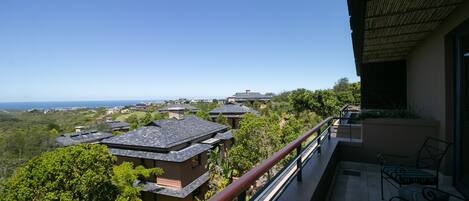 A balcony with a view of a residential area and the sea.
