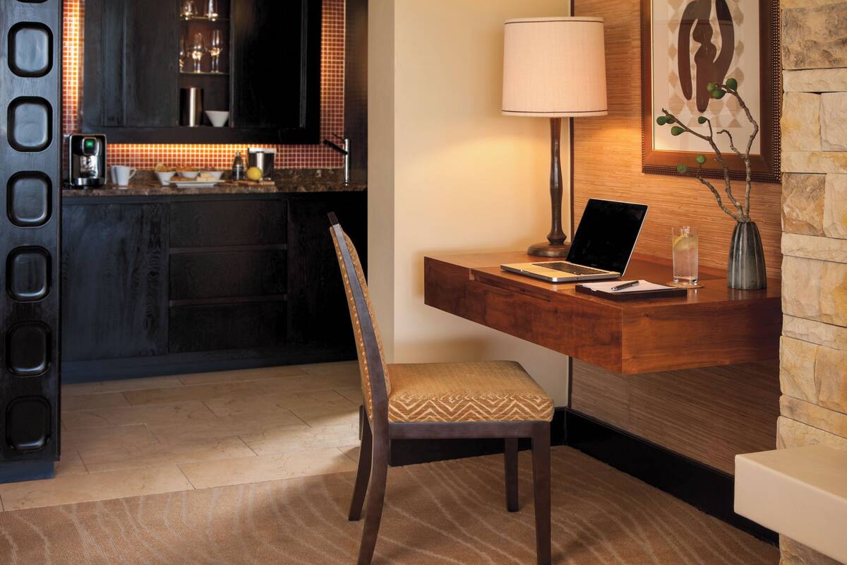 A modern kitchen with dark cabinetry, a coffee machine, and a countertop with a bowl of fruit.