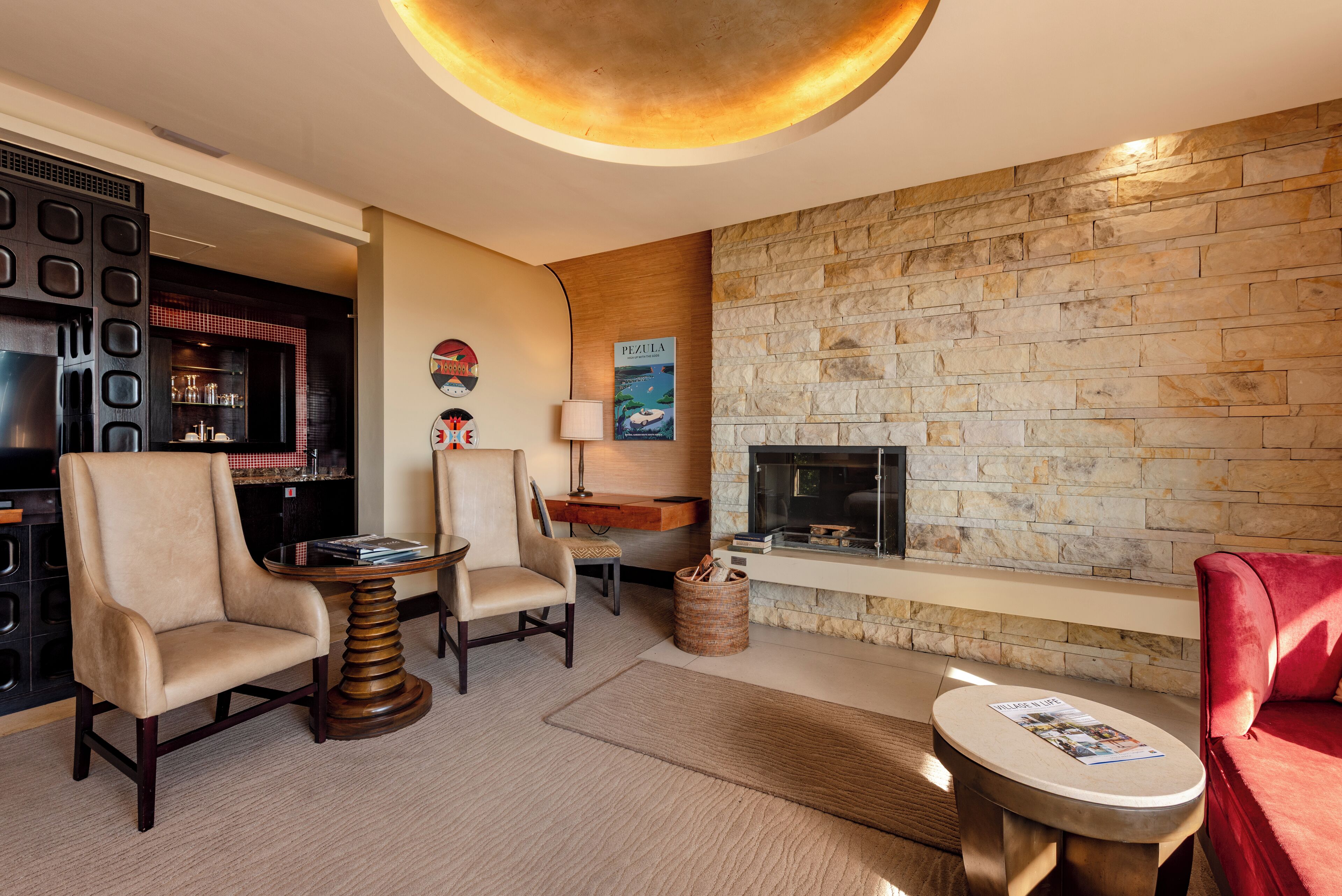 A modern living room with a stone wall, a fireplace, and a bar area.