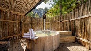 A wooden deck with a hot tub, wooden steps, and a bamboo fence.