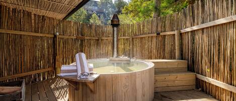 A hot tub with a wooden deck and bamboo walls.