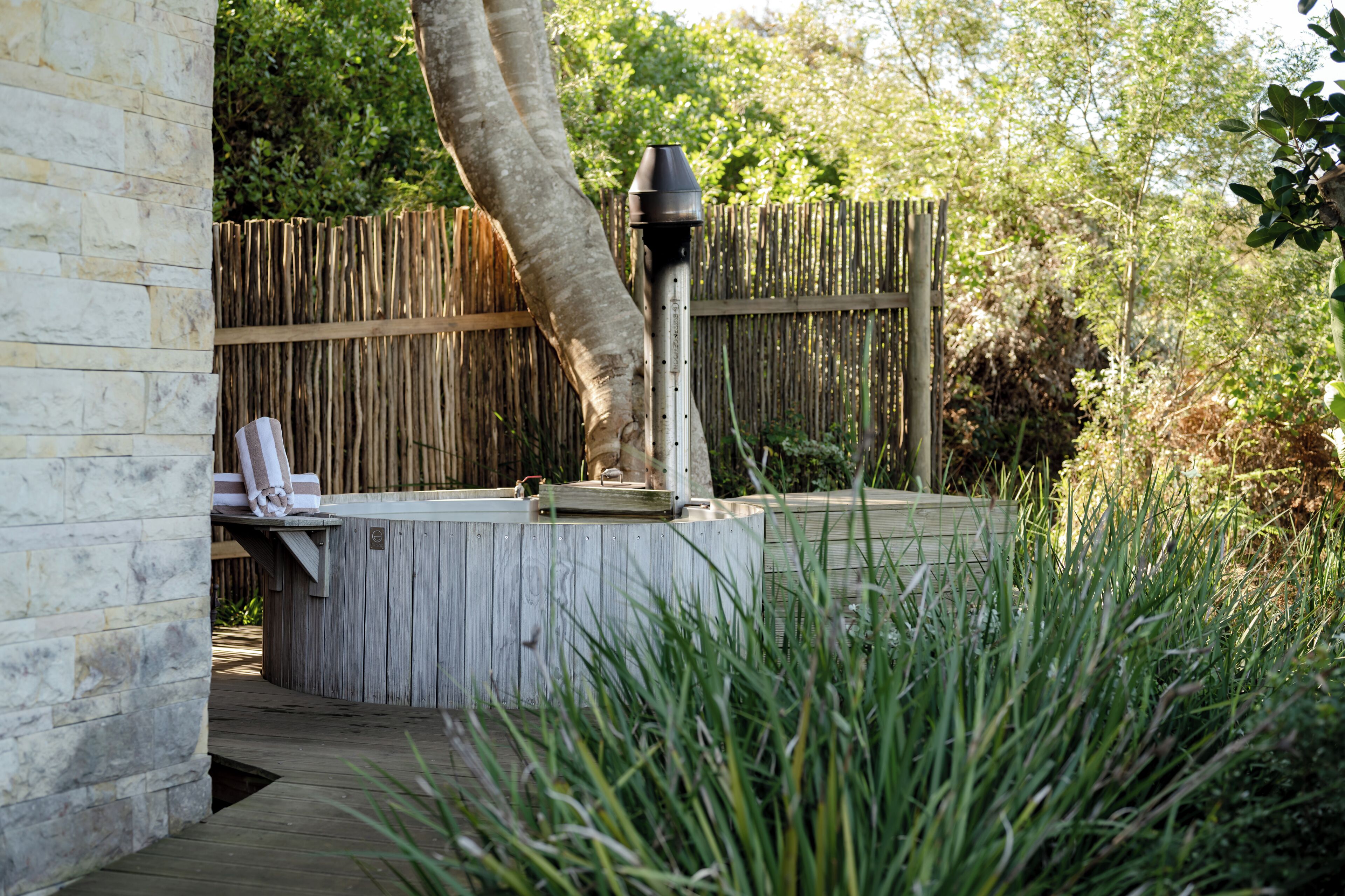 Una terraza de madera con un jacuzzi, un perchero y una valla de madera al fondo.