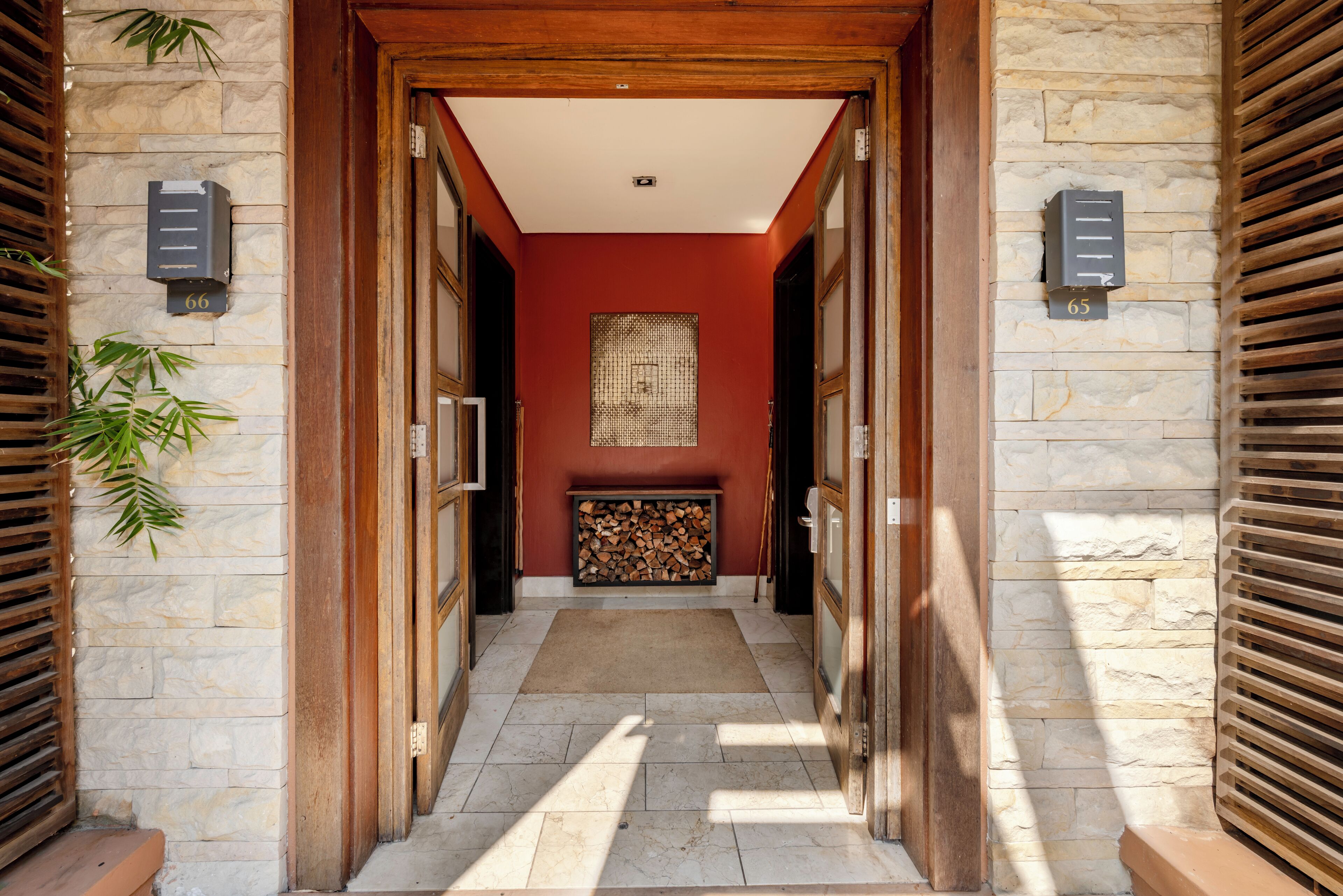 A hallway with stone walls, wooden doors, and a red accent wall.