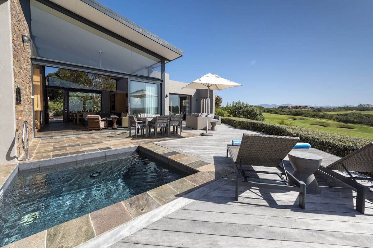 A modern outdoor pool area with a view of a golf course.